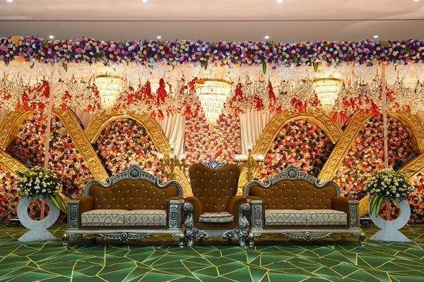 Floral arch royal wedding stage setup with twin golden thrones